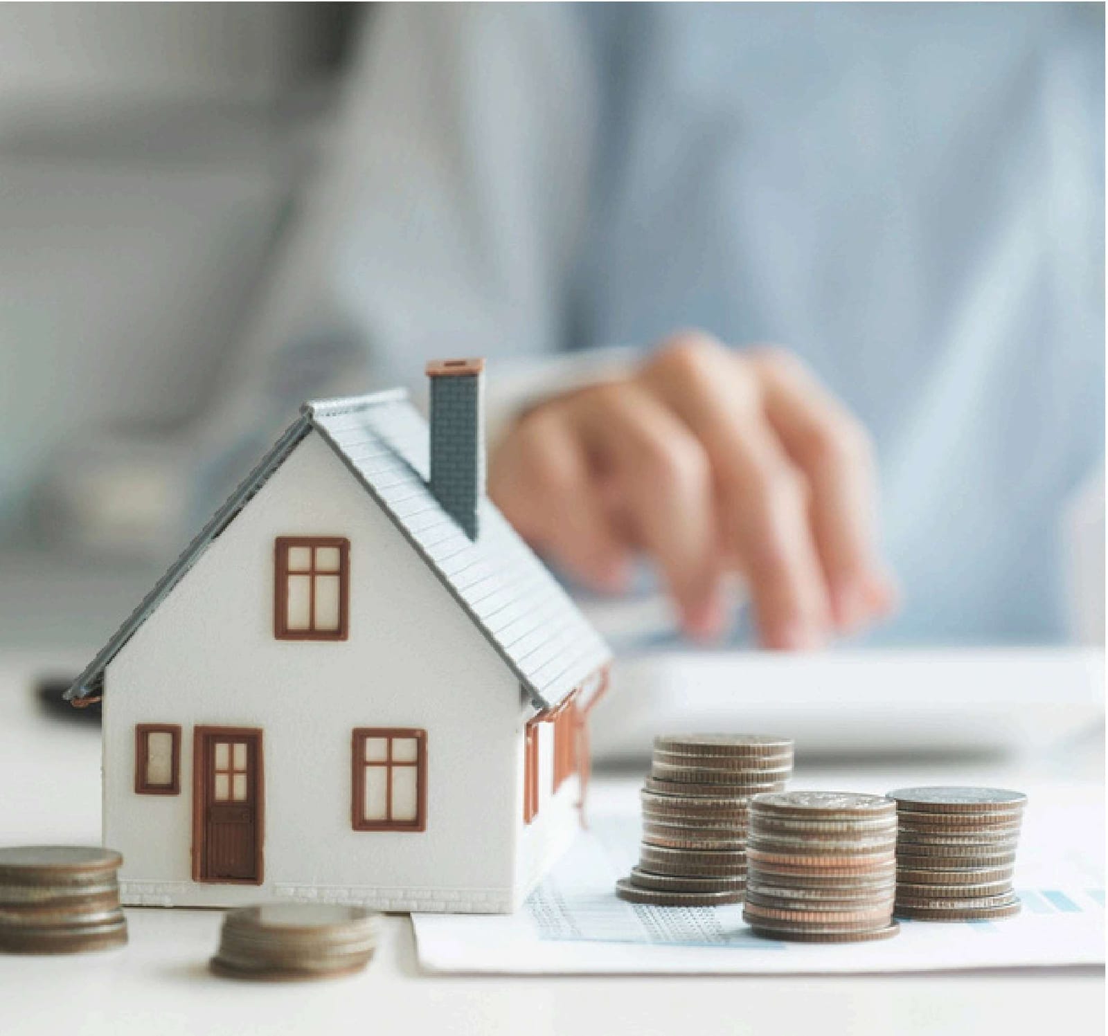 A model house beside stacked coins, representing property value and taxes