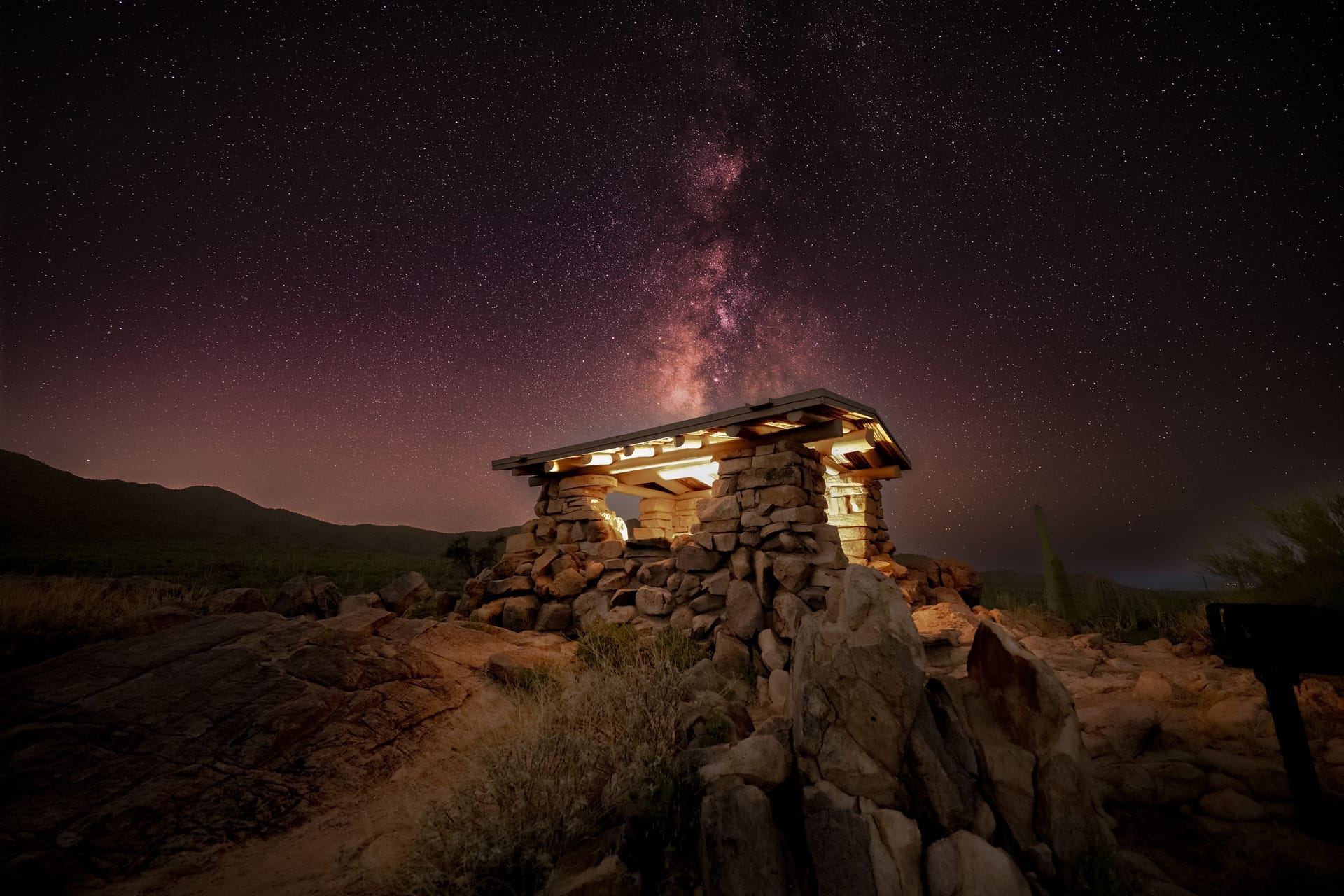 Rustic stone cabin illuminated beneath the stunning Milky Way in Tucson, Arizona night sky