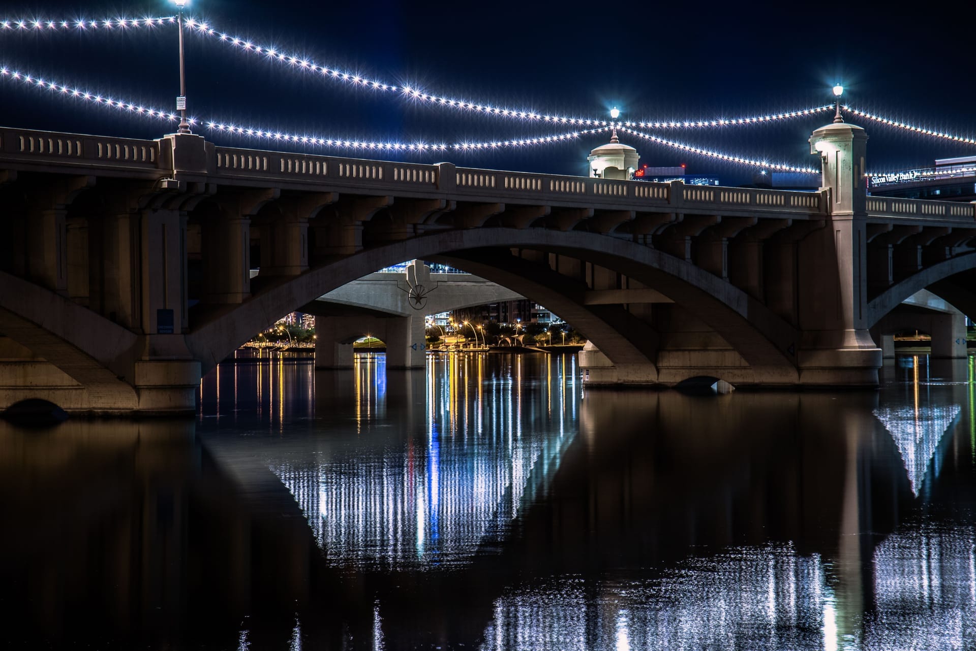 Stunning night view of the illuminated Tempe Town Lake Bridge, reflecting in the water