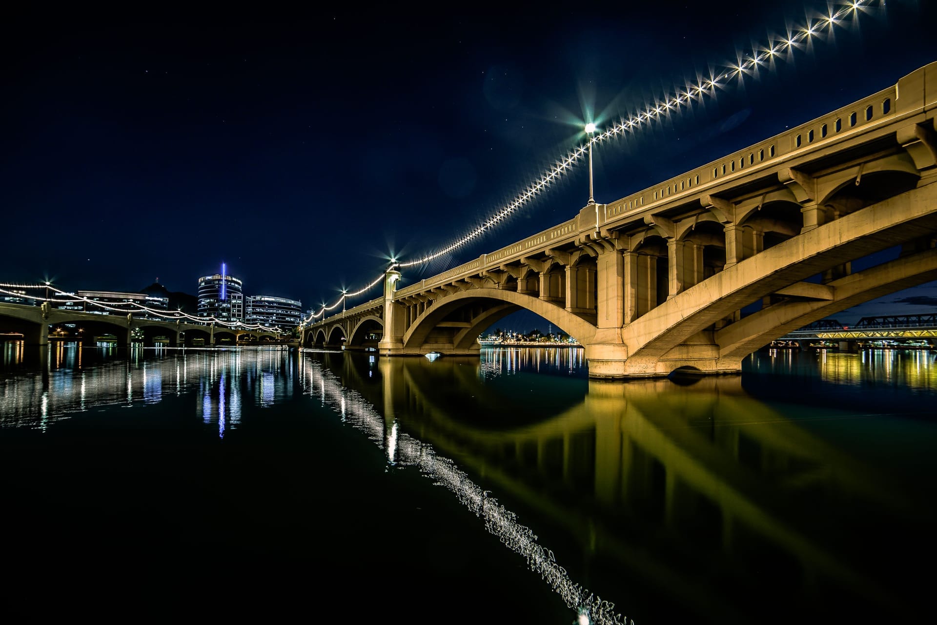 Stunning night view of the illuminated bridge at Tempe Town Lake, Arizona, reflecting in the water