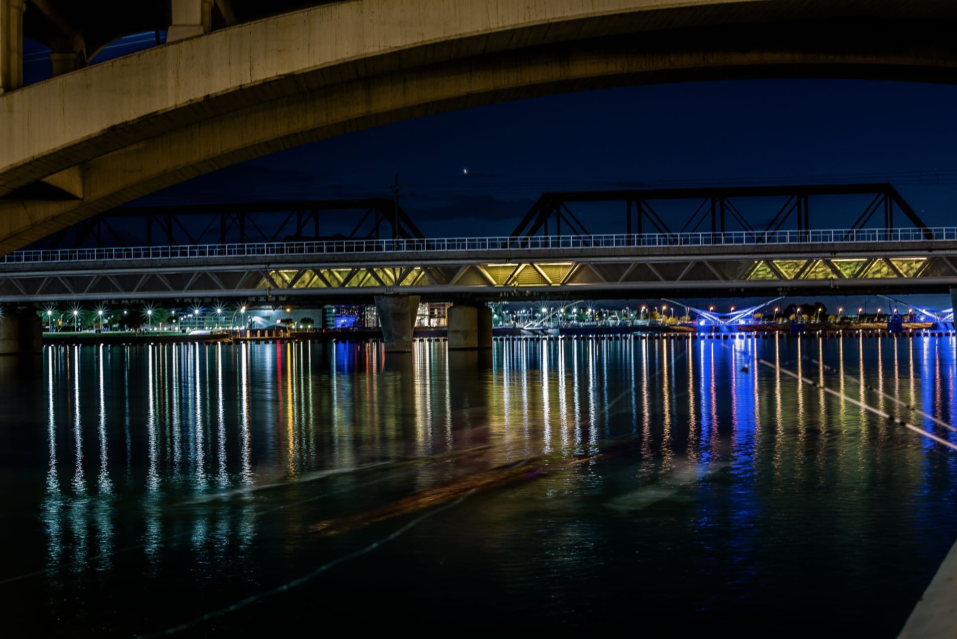 Night view of illuminated bridge reflecting light in water, located in Tempe, Arizona
