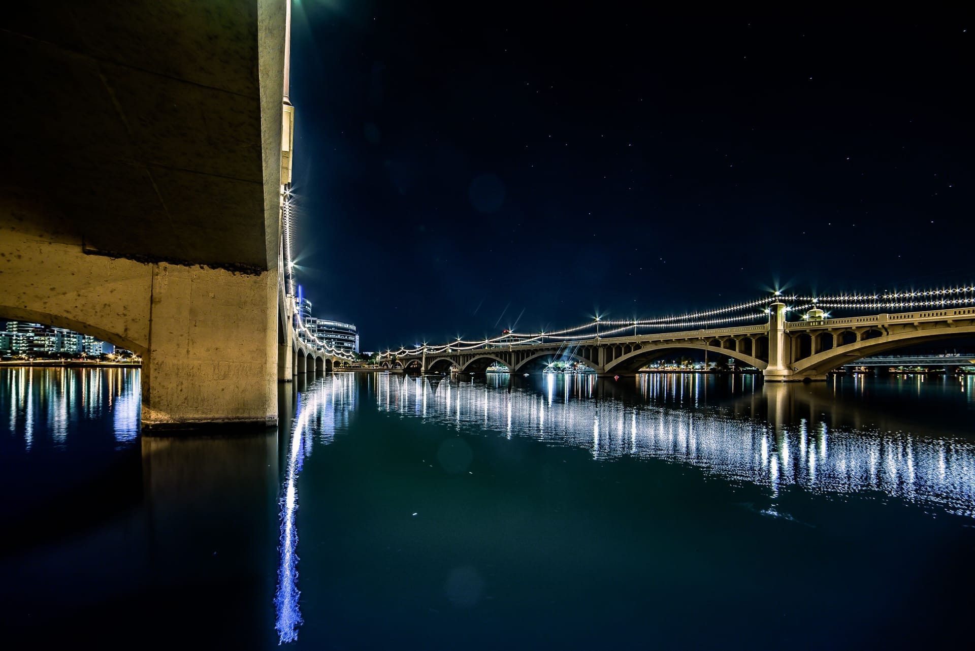 Stunning nighttime shot of Tempe Town Lake bridge with reflections, stars, and city lights