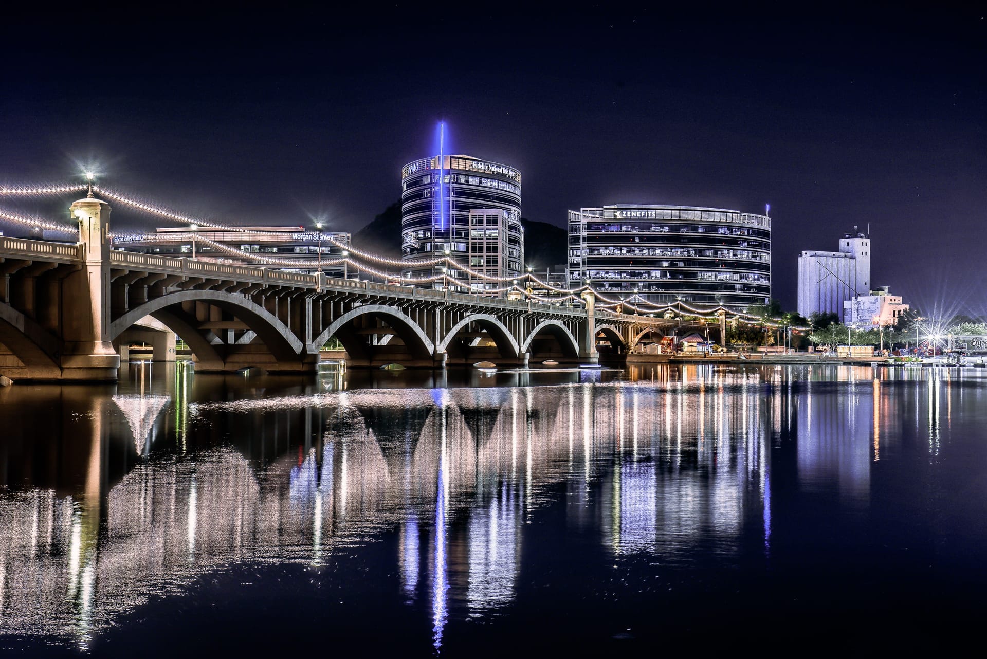 Night view of the illuminated Tempe Town Lake Bridge reflecting on the water surface